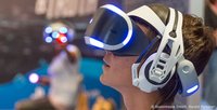 Person mit Virtual-Reality-Brille, die immersive VR-Technologie erlebt, wie sie auf Messen angeboten wird.